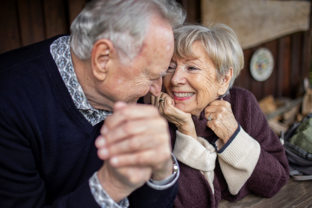 male and female older adults sitting close and holding hands